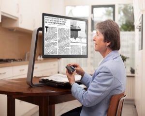 a woman using a desktop magnifier to read a newspaper